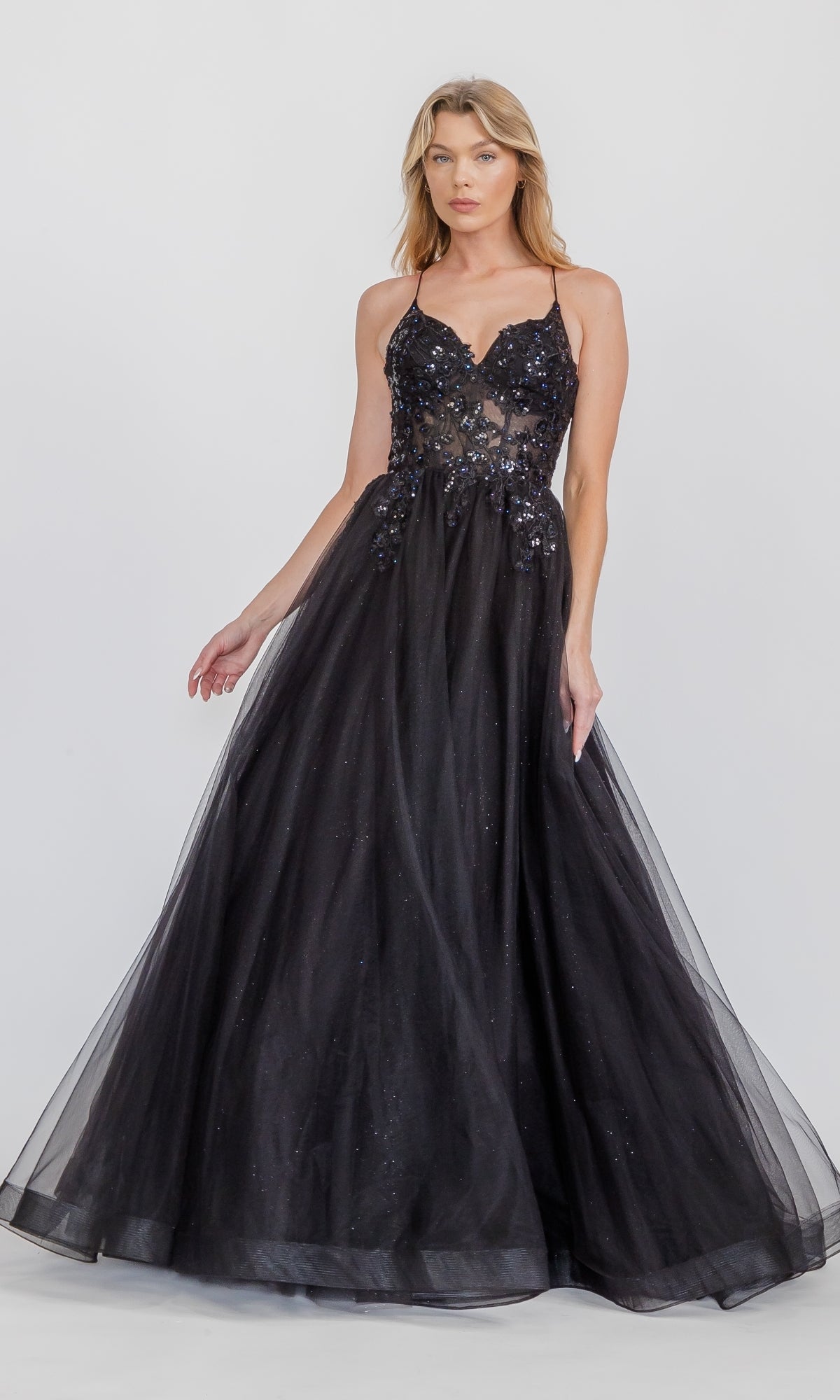 A woman wears the Eureka 9960 Lace-Up Corset Long Prom Ball Gown, a sleeveless black floor-length dress with a fitted bodice and sequin embellishments, standing against a plain light background.